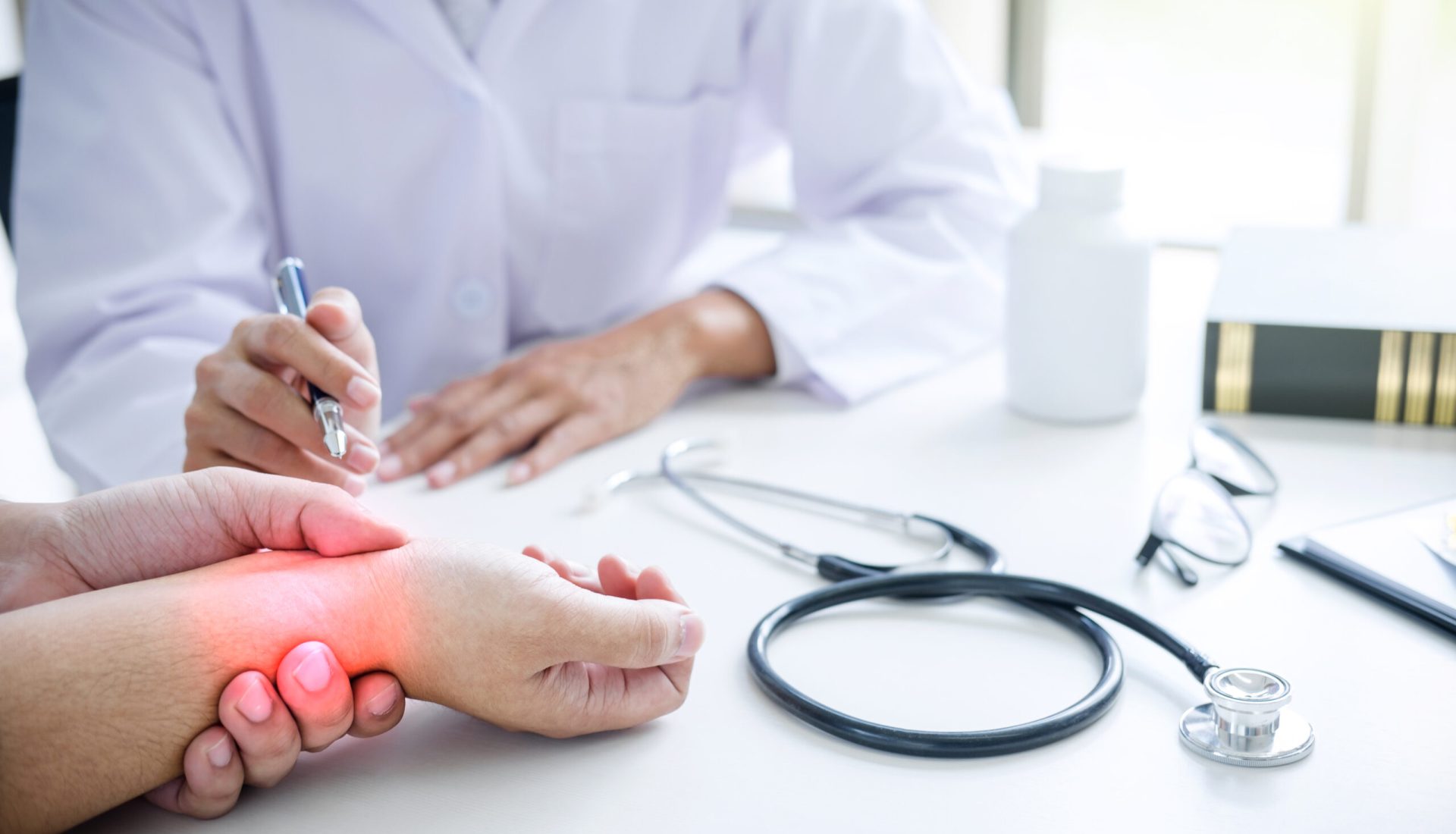 Doctor in white coat taking and checking the Patient's wrist pain during the examination.