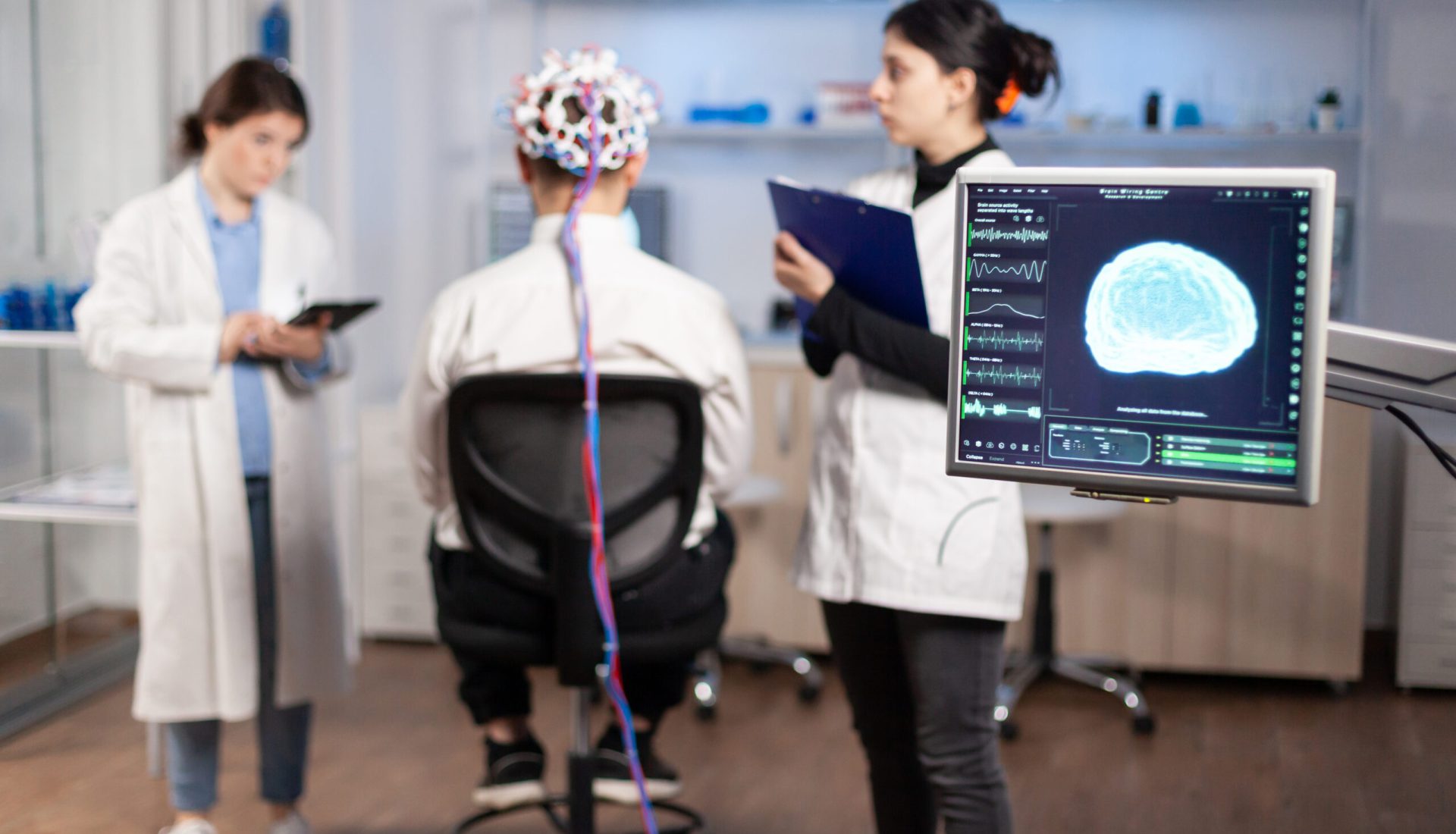 Man patient wearing performant eeg headset scanning brain electrical activity in neurological research laboratory while medical researcher controlling it, examining nervous system, nurse taking notes